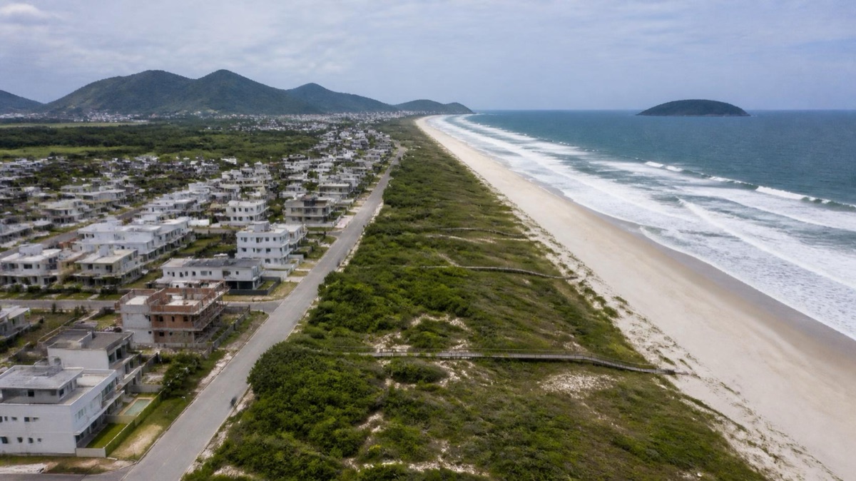 AI-generated illustration of Novo Campeche in Florianópolis, Brazil, with new houses and condominiums behind the dunes and the beach